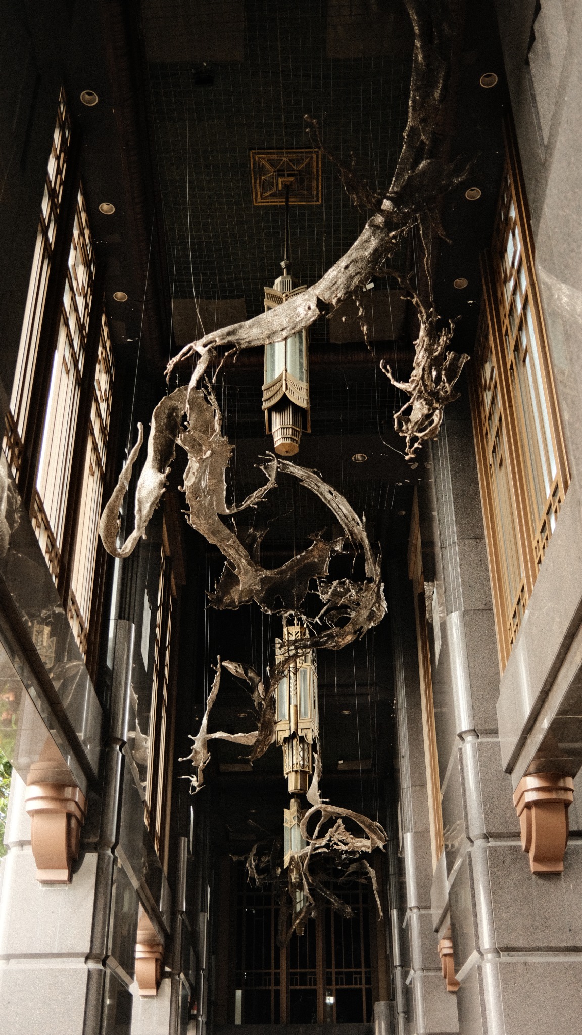 Suspended sculptural installation inside a dramatic architectural corridor