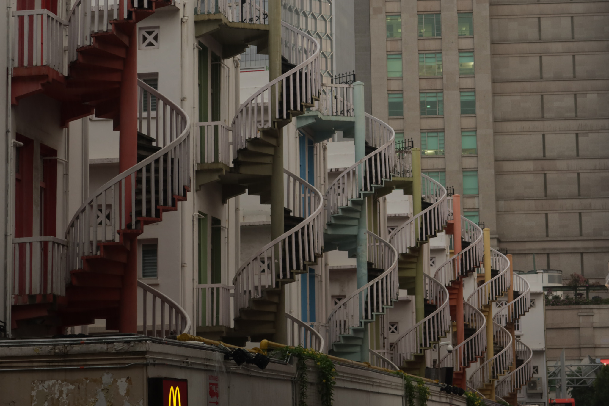 Repeated colourful spiral staircases against urban architecture