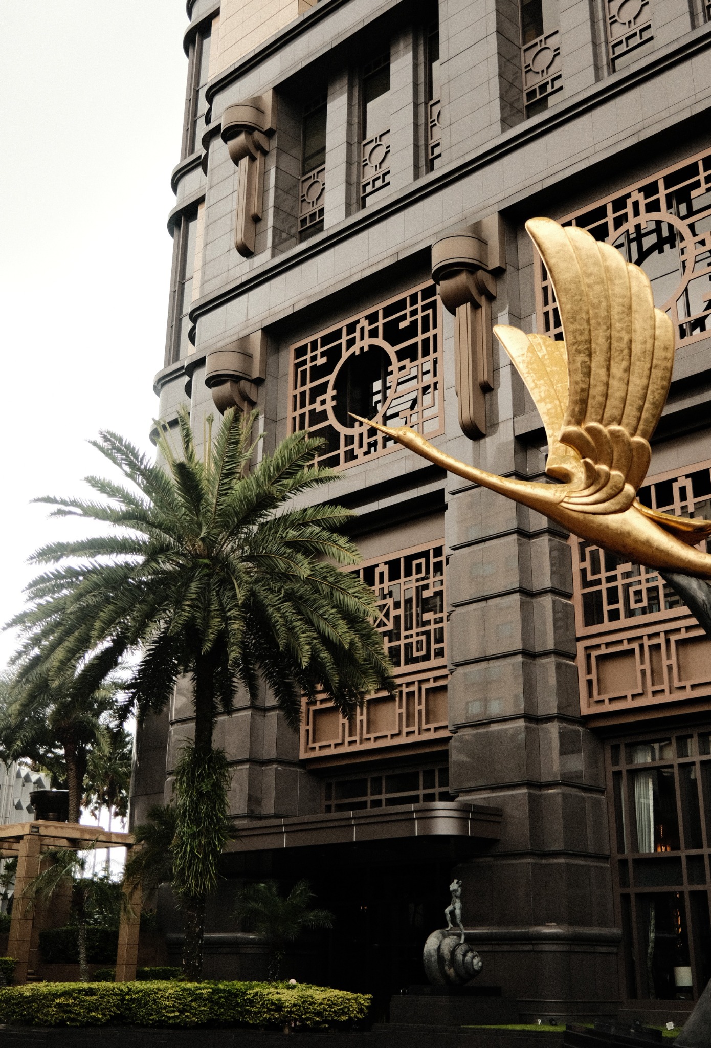 Architectural facade with golden bird sculpture and palm tree