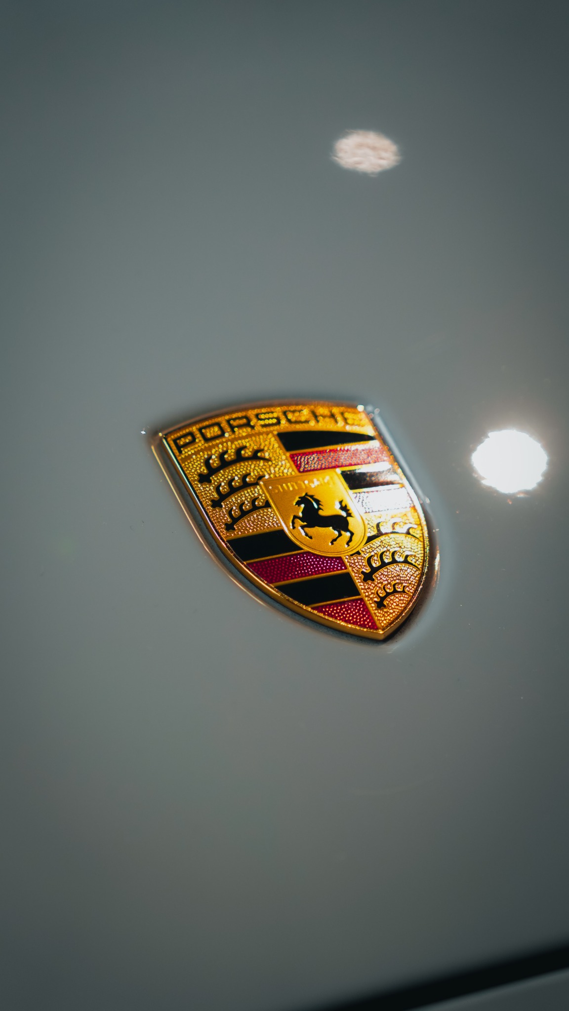 Close-up detail of a Porsche crest on white bodywork
